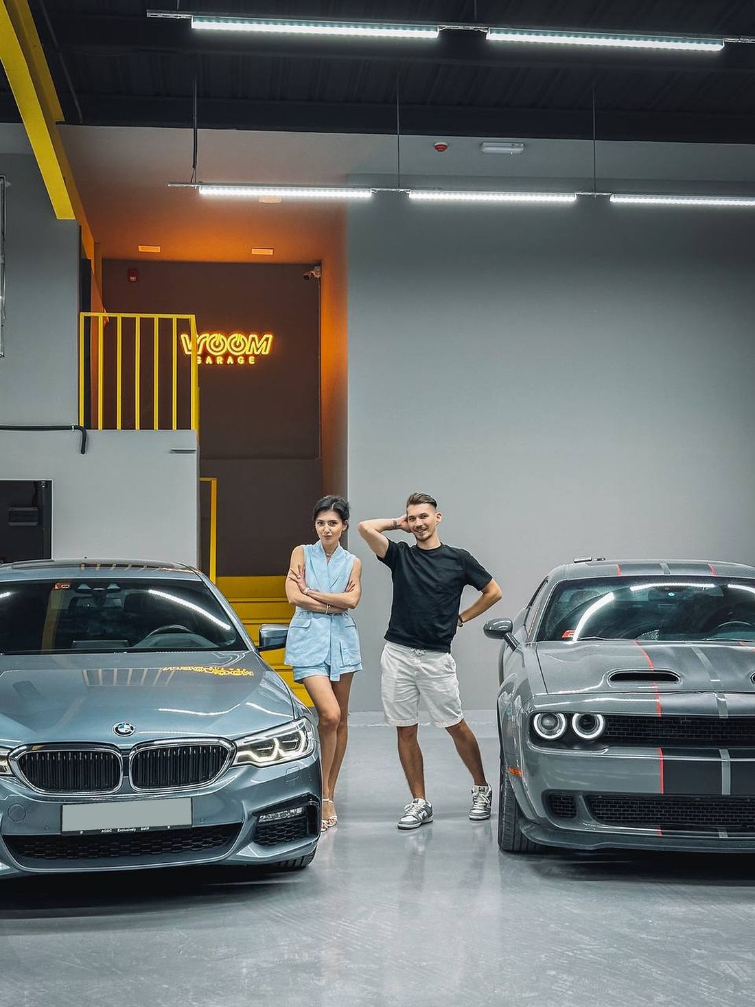 Екатерина и Евгений, основатели Vroom Garage, в гараже между BMW и Dodge Challenger